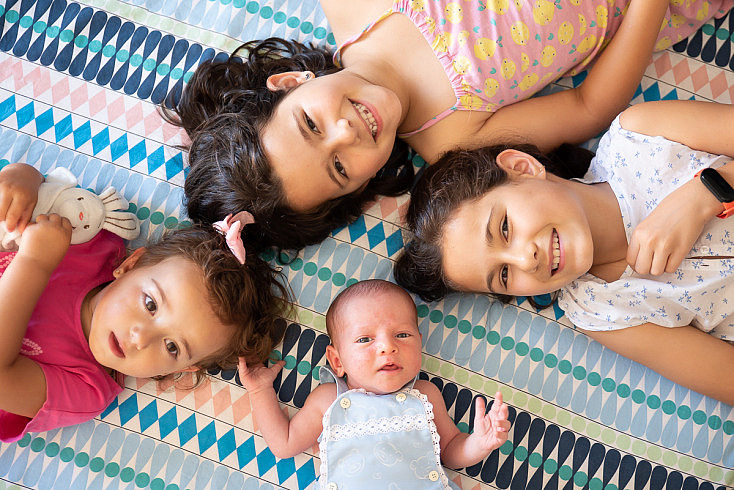 Sesión Newborn - Bebé rodeado de hermanas